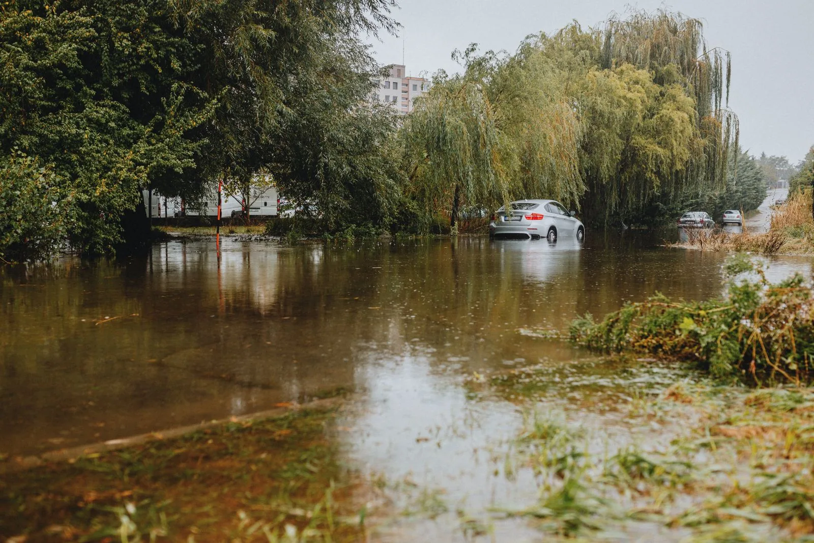 Car driving through a flooded urban road after heavy rain