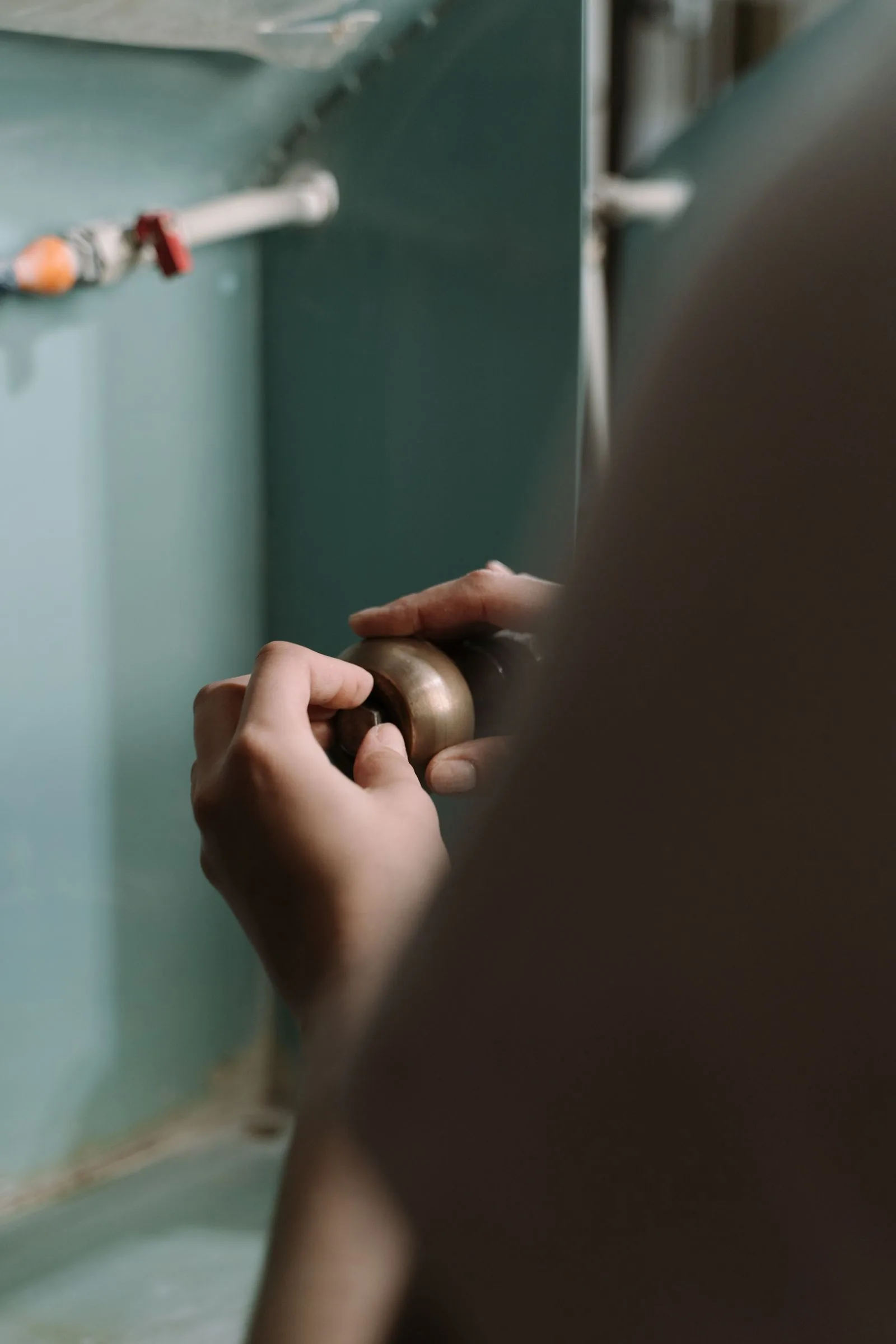 Close-up of hands adjusting a pipe under a kitchen sink